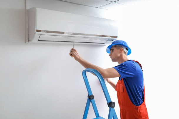 Techniker repariert Klimaanlage in Innenräumen - Foto, Bild