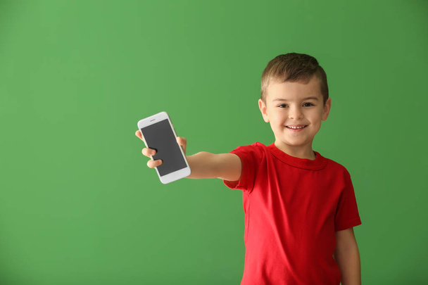 niedlicher kleiner Junge mit Smartphone auf farbigem Hintergrund - Foto, Bild