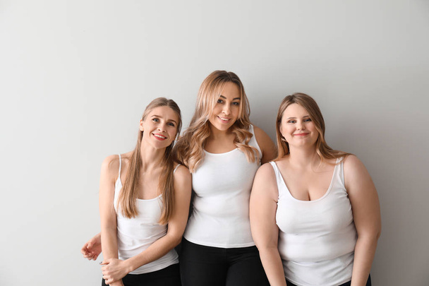 Beautiful young women on light background. Concept of body positivity - Photo, Image