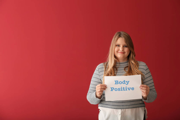 Gyönyörű, plusz méretű girl gazdaság papírlap a háttér szín a test pozitív szöveggel - Fotó, kép