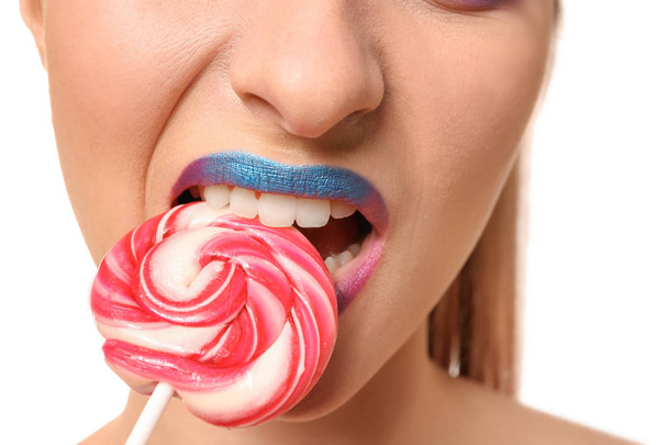 Beautiful young woman with unusual makeup and sweet lollipop on white background, closeup - 写真・画像