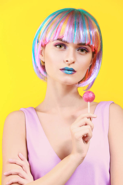 Güzel genç ve kadın ile olağandışı makyaj renk arka plan üzerinde tatlı lolipop - Fotoğraf, Görsel