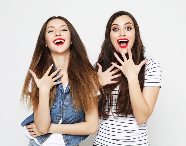 Two young girl friends having fun. Both making surprised faces. - Foto, imagen