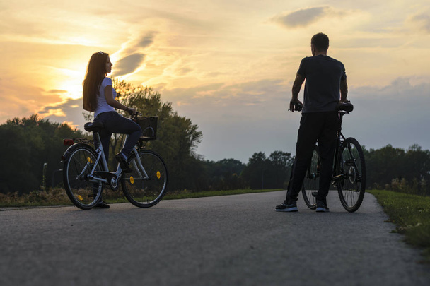 νεαρό ζευγάρι με ποδήλατα που στέκονται στο δρόμο το βράδυ - Φωτογραφία, εικόνα
