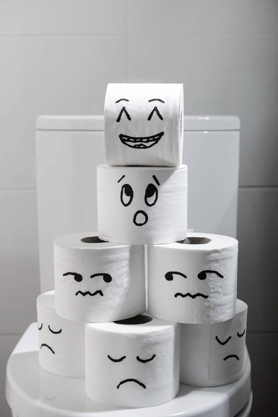 Papierrollen mit lustig gezeichneten Gesichtern auf Toilettenschüssel - Foto, Bild