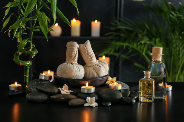 Kaunis kylpylä koostumus kiviä, kynttilöitä ja kasviperäisiä pusseja tummalla pohjalla
 - Valokuva, kuva