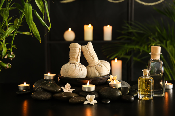 Composição bonita do spa com pedras, velas e sacos de ervas no fundo escuro
 - Foto, Imagem