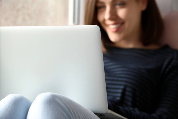 Young woman with laptop sitting on window sill - Foto, Imagen