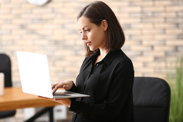Молода жінка працює з ноутбуком в офісі
 - Фото, зображення