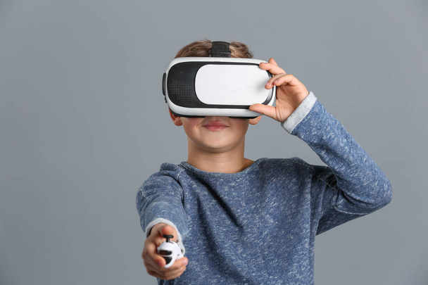 Cute boy with virtual reality glasses on grey background - Photo, Image