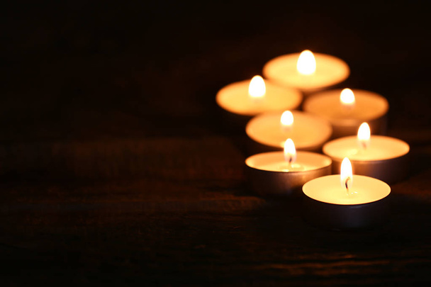 Belas velas acesas em madeira na escuridão
 - Foto, Imagem