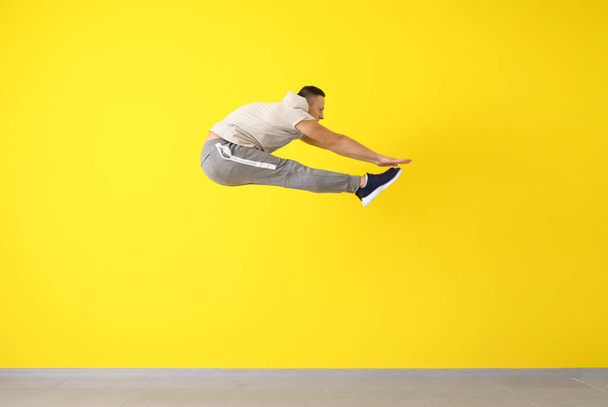 Молодий чоловік танцюрист стрибає біля кольорової стіни
 - Фото, зображення