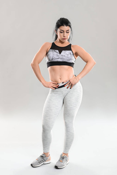 Sporty muscular woman on grey background - Fotoğraf, Görsel