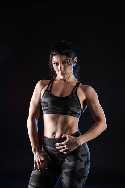 Sporty muscular woman on dark background - 写真・画像