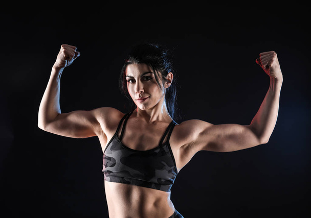 Спортивная мускулистая женщина на тёмном фоне
 - Фото, изображение