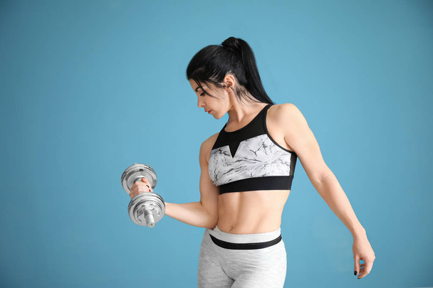 Mulher muscular desportiva com haltere no fundo de cor
 - Foto, Imagem