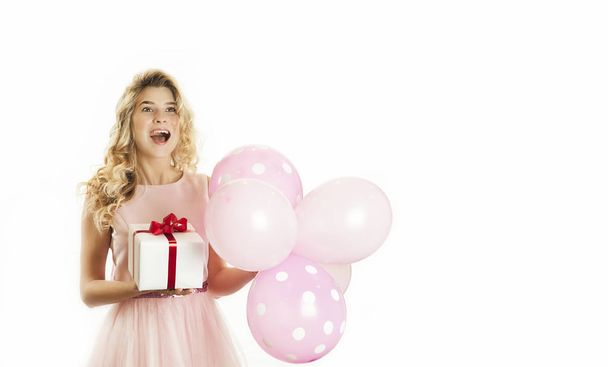 Young beautiful girl with a white gift with a red bow and balls in the hands rejoices on an isolated white background. Valentine day concept. Lovers day. - Foto, imagen