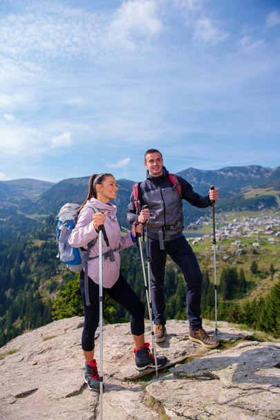 Wandelaars met rugzakken ontspannen op de top van een berg en genieten van het uitzicht op de vallei - Foto, afbeelding