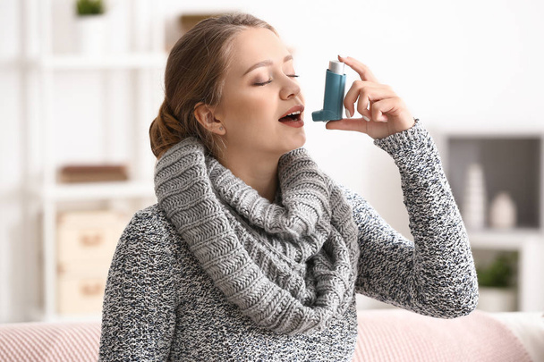 Young woman with inhaler having asthma attack at home - Foto, afbeelding