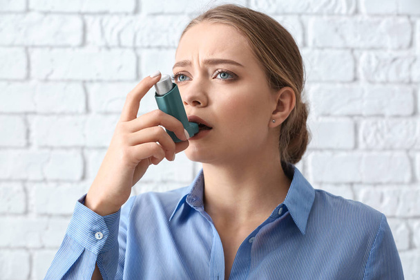 Young woman with inhaler having asthma attack on white background - Foto, Imagen