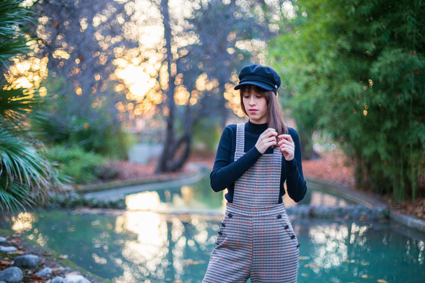 Young woman with stylish clothes posing in a paradisiacal park at sunset - Foto, afbeelding