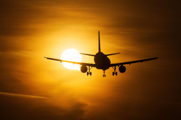 Silhouette di un aereo aereo sopra il sole con bellissime nuvole rosse sullo sfondo
 - Foto, immagini