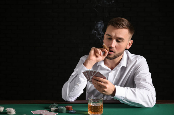 Young man playing poker in casino - Foto, imagen