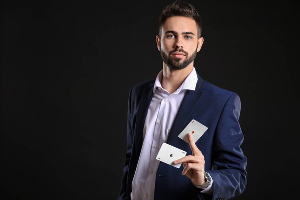 Handsome young man with cards on dark background - Фото, зображення