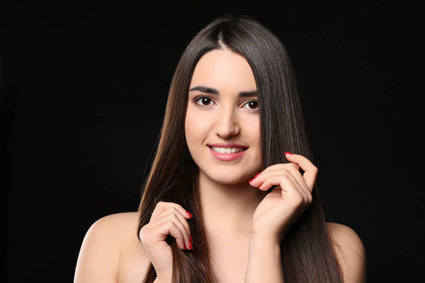 Portrait of young woman with beautiful straight hair on dark background - Foto, Bild
