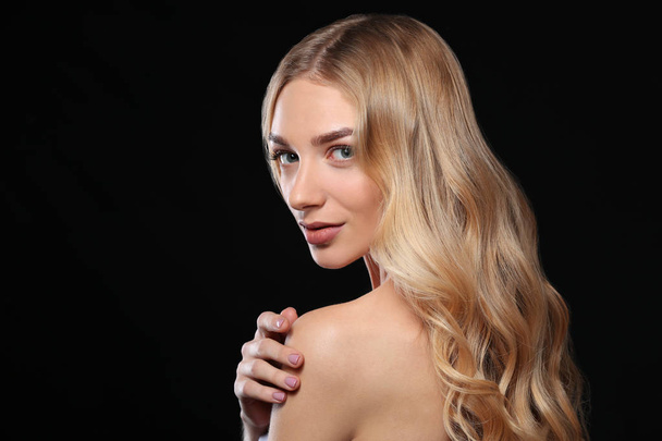 Młoda kobieta z pięknymi kręconymi włosami na ciemnym tle - Zdjęcie, obraz
