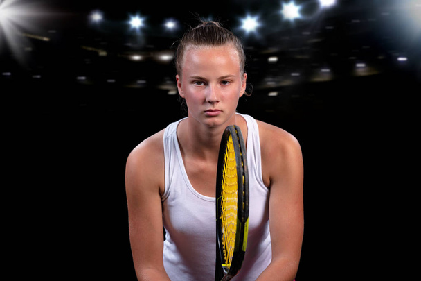 Beautiful girl tennis player with a racket on dark background with lights - Foto, afbeelding