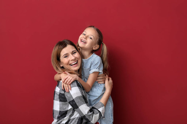 Porträt einer glücklichen Mutter mit Tochter auf farbigem Hintergrund - Foto, Bild