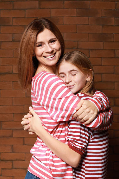 Ritratto di madre e figlia felice su sfondo mattone
 - Foto, immagini
