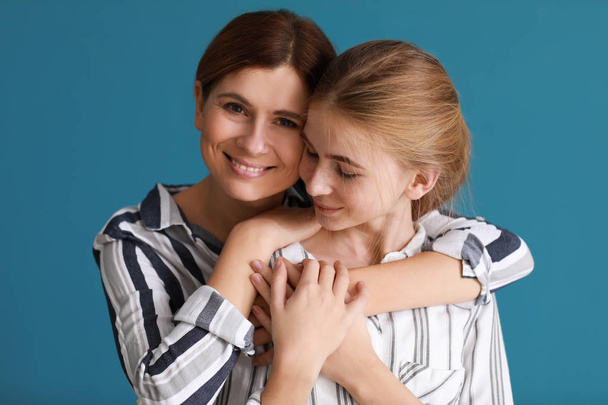 Portret van gelukkige moeder en dochter op kleur achtergrond - Foto, afbeelding