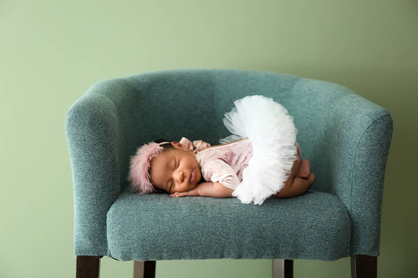 niedliches afrikanisch-amerikanisches Baby schläft im weichen Sessel auf farbigem Hintergrund - Foto, Bild