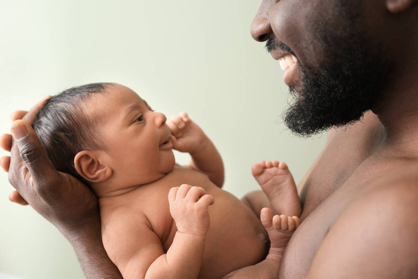 Happy African-American father with little baby on color background - Фото, изображение
