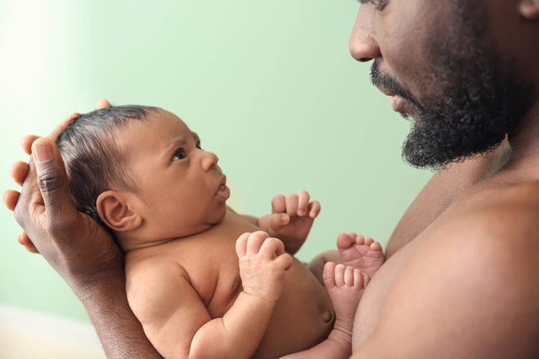 Feliz pai afro-americano com pouco bebê no fundo de cor
 - Foto, Imagem