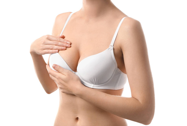 Nuori nainen tarkistaa rintansa valkoiselta taustalta. Syöpätietoisuuden käsite
 - Valokuva, kuva