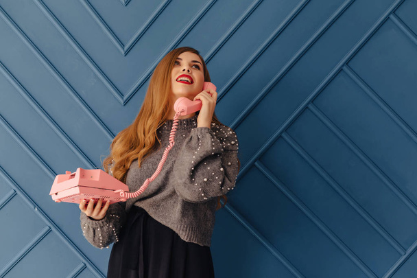 attractive stylish young girl with retro pink phone on simple aqua background emotions - Photo, Image