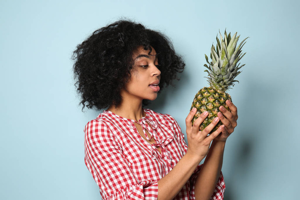 Портрет молодой афроамериканки с ананасом на цветном фоне
 - Фото, изображение