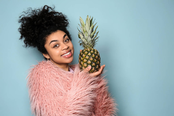 Portrait of young African-American woman with pineapple on color background - Photo, Image
