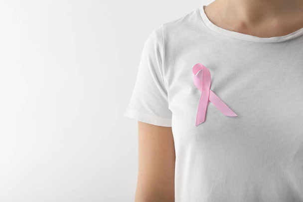 Woman with pink ribbon on light background. Breast cancer awareness concept - Photo, Image