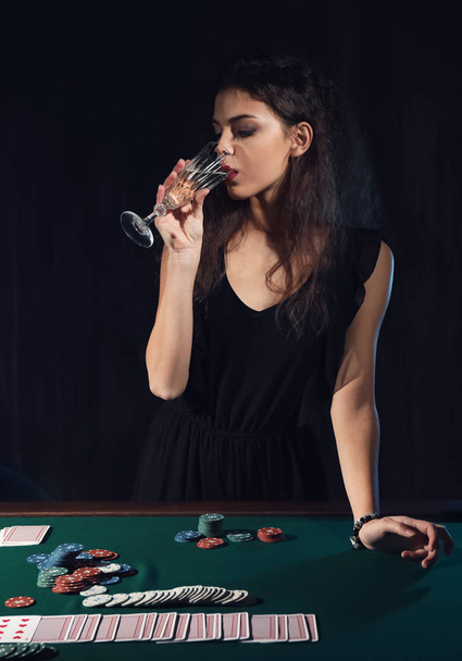 Beautiful female player at table in casino - Foto, afbeelding