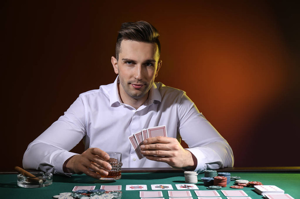 Красивий чоловічий гравець за столом в казино
 - Фото, зображення