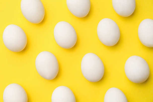 Many chicken eggs on color background - Foto, afbeelding