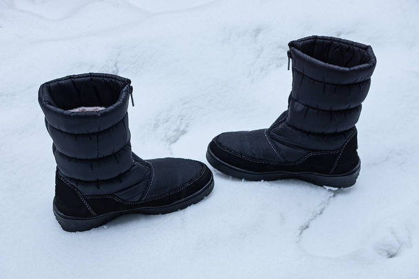 two big black boots of matter standing on white snow on the street - Φωτογραφία, εικόνα