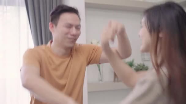 Asian couple dance while listen to music in living room at home, sweet couple enjoy love moment while lying on the sofa when relax at home. Lifestyle couple relax at home concept. - Video