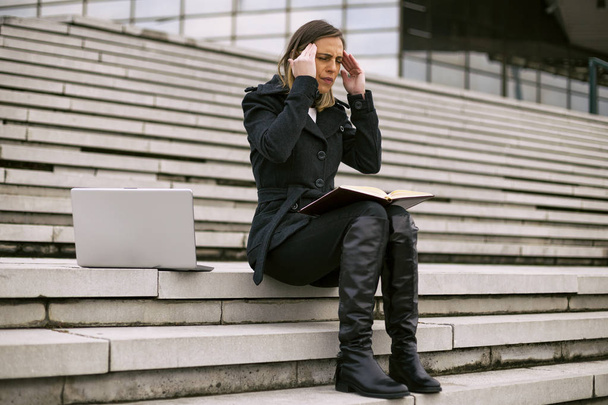 Businesswoman  having a headache  while working outdoor.Toned image. - Fotó, kép