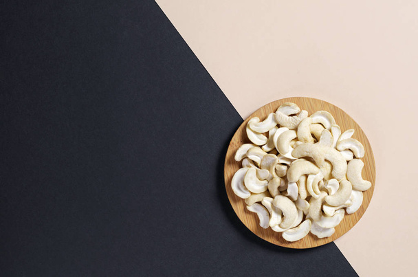 Cashew nuts halves on two-tone background, top view with copy space  - Photo, Image