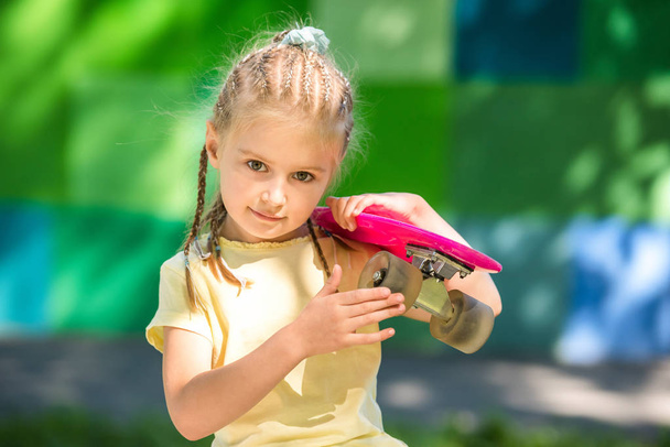 cute little girl with a skateboard on her shoulder - 写真・画像